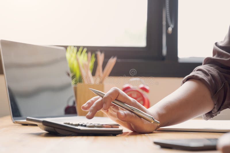 Close up Businesswoman using calculator and laptop for do math finance on wooden desk in office and business working background,, Close up Businesswoman using calculator and laptop for do math finance on wooden desk in office and business working background, tax, accounting, statistics and analytic research concept