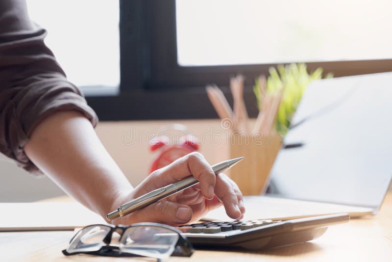 Close up Business woman using calculator and laptop for do math finance on wooden desk in office and business working background,, Close up Business woman using calculator and laptop for do math finance on wooden desk in office and business working background, tax, accounting, statistics and analytic research concept