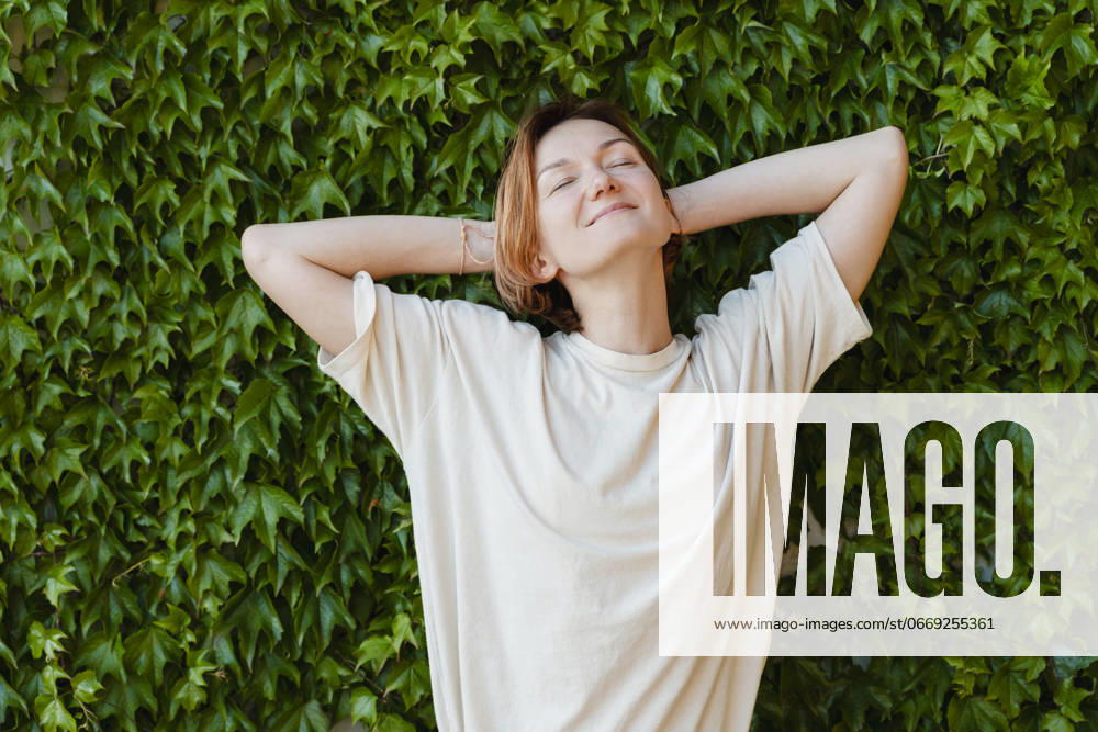 Smiling woman with hands behind head relaxing on plants model released, Symbolfoto, NDEF01870