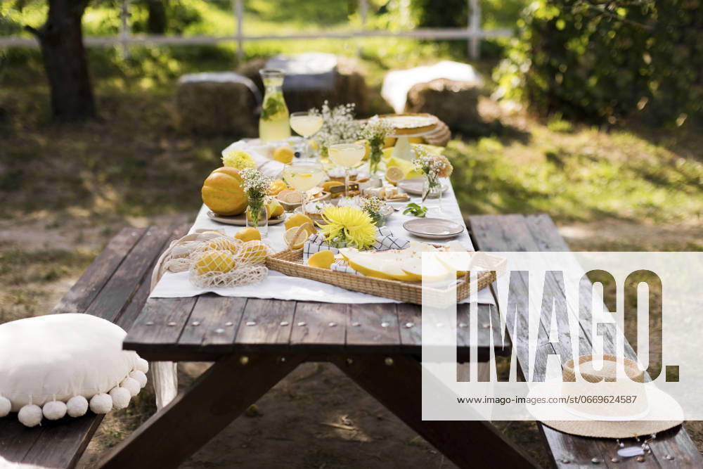 IMAGO Creative, Lifestyle, Feste im Garten #2 Wooden picnic table decorated with various food in garden, ONAF00859