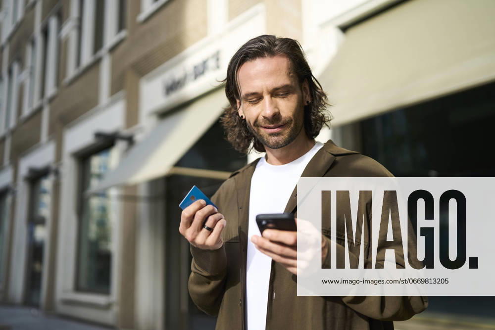 Smiling mature man using smart phone doing online shopping through credit card on sunny day model released, Symbolfoto, PNEF02939