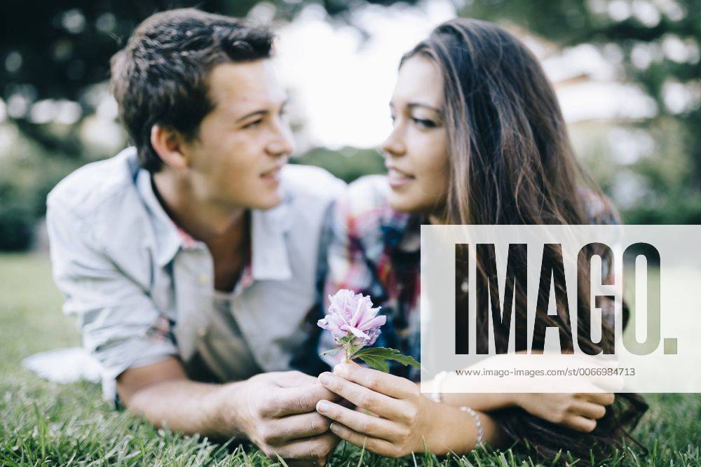 Young couple in love lying on a meadow in a park looking at each other JRFF000131