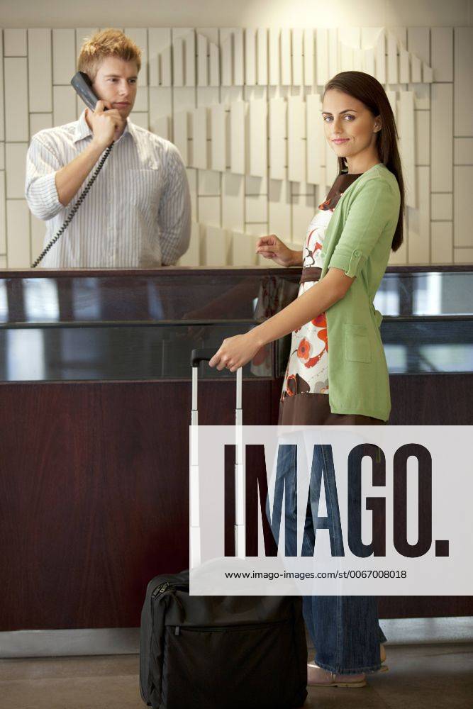Woman standing at hotel reception with rolling suitcase model released Symbolfoto property released TOYF001387
