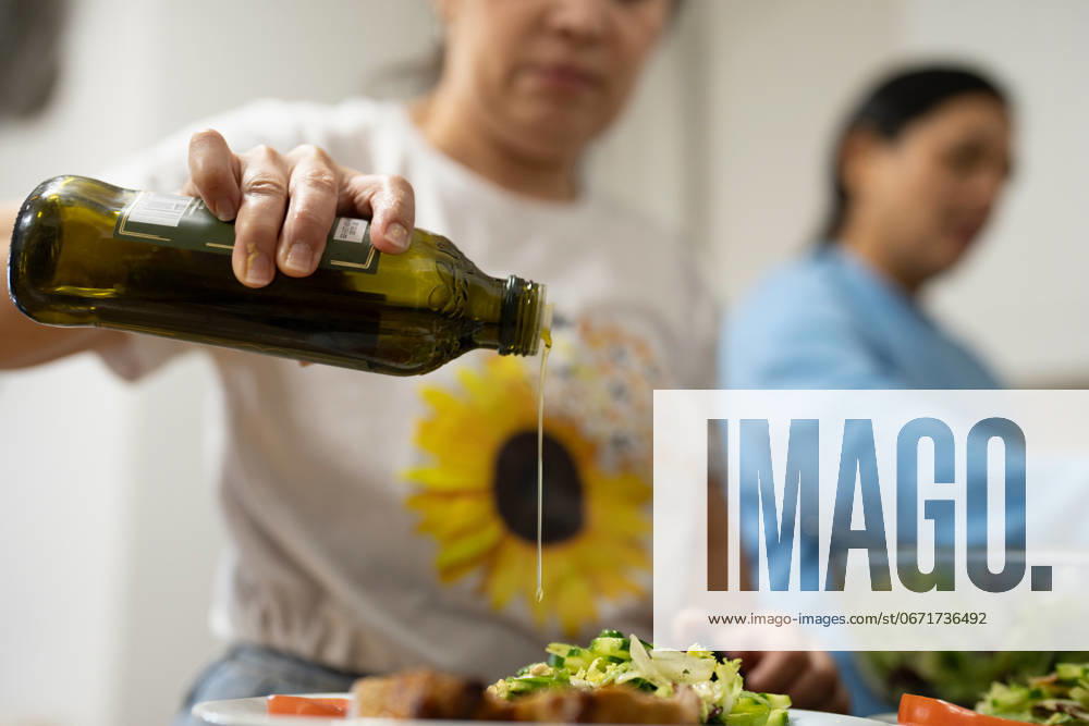 Woman using olive oil for meal, close up model released