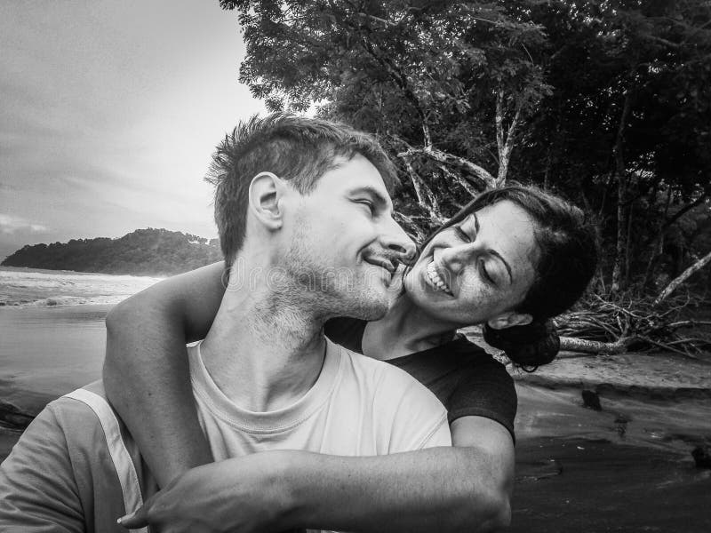 Smiling Girlfriend Embracing Boyfriend At Beach., Happy young romantic couple in love looking each other in the eye. Smiling Girlfriend Embracing Boyfriend At Beach. Can be used with similar image no. 130767762.