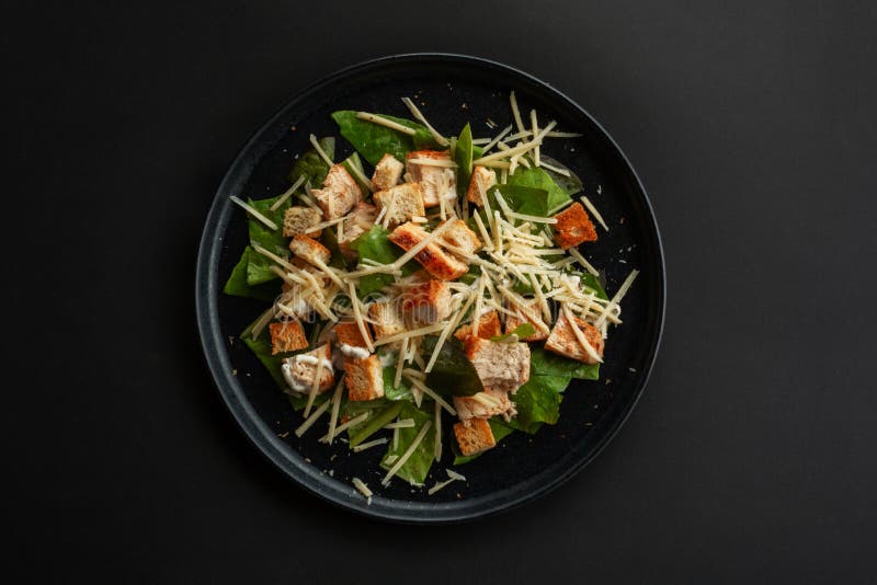 Caesar salad top view, Caesar salad top view on black table over black table background