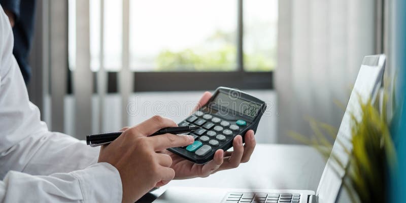 Close up Business woman using calculator and laptop for do math finance on wooden desk in office and business working background,, Close up Business woman using calculator and laptop for do math finance on wooden desk in office and business working background, tax, accounting, statistics and analytic research concept