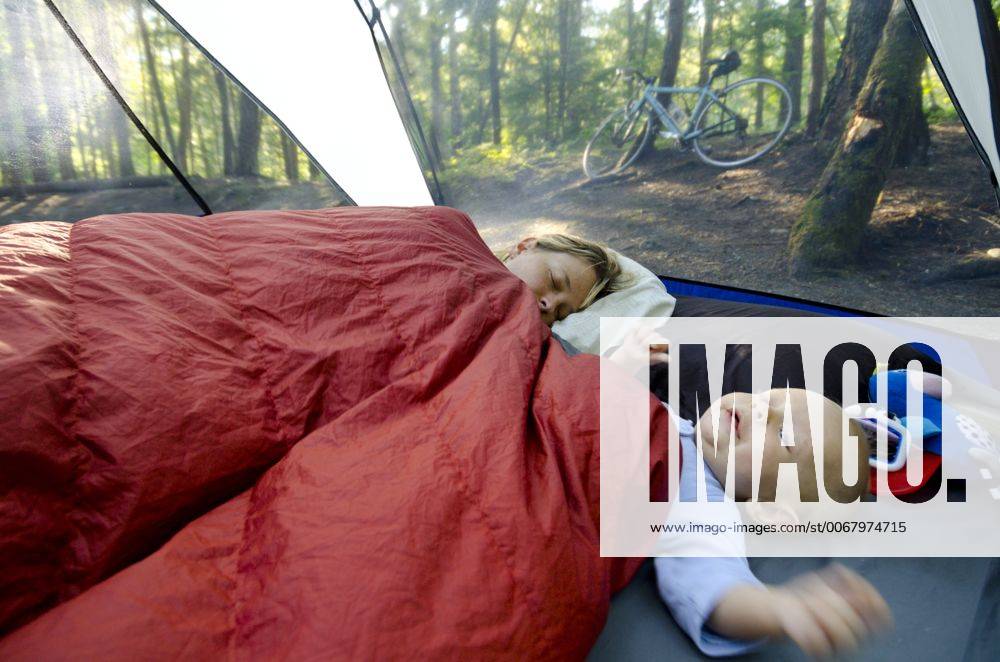 A young mother and her one year old boy in a tent on a camping trip. Mom is still trying to sleep. Rosebery Provincial Park, British Columbia acp79394 StevexOgle