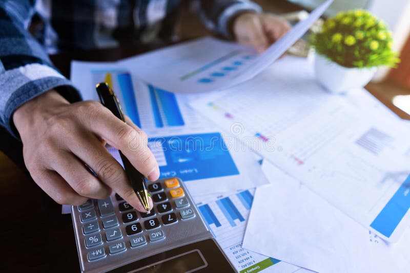 Close up businessman using calculator and reading paper document about business data, accountancy document, graph profit company, Close up businessman using calculator and reading paper document about business data, accountancy document, graph profit company.