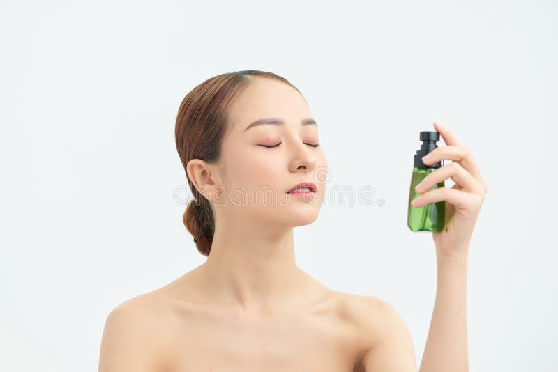 Beautiful Asian woman applying spray water on face on neutral background, Beautiful Asian woman applying spray water on face on neutral background. model released