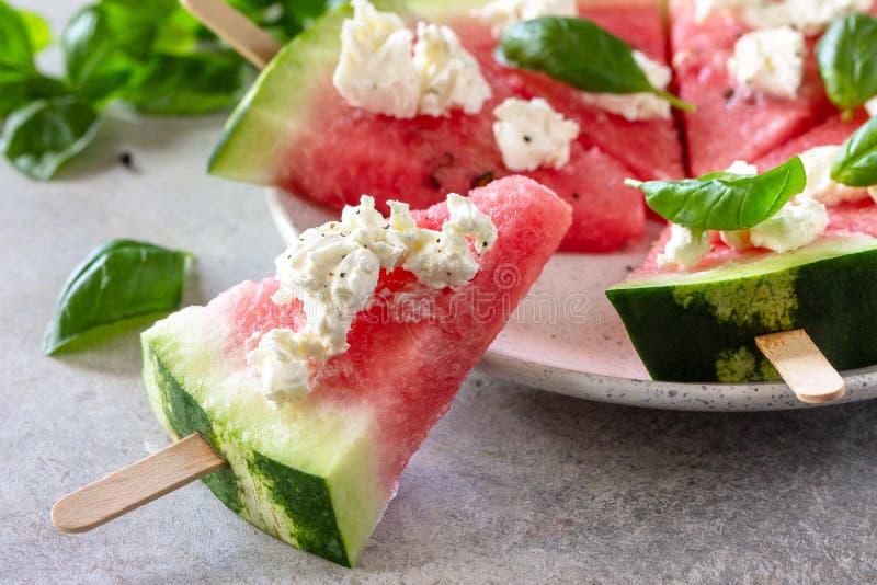 Healthy seasonal dieting and nutrition, summer snack. Watermelon pizza with feta cheese and basil on a gray stone tabletop., Healthy seasonal dieting and nutrition, summer snack. Watermelon pizza with feta cheese and basil on a gray stone tabletop