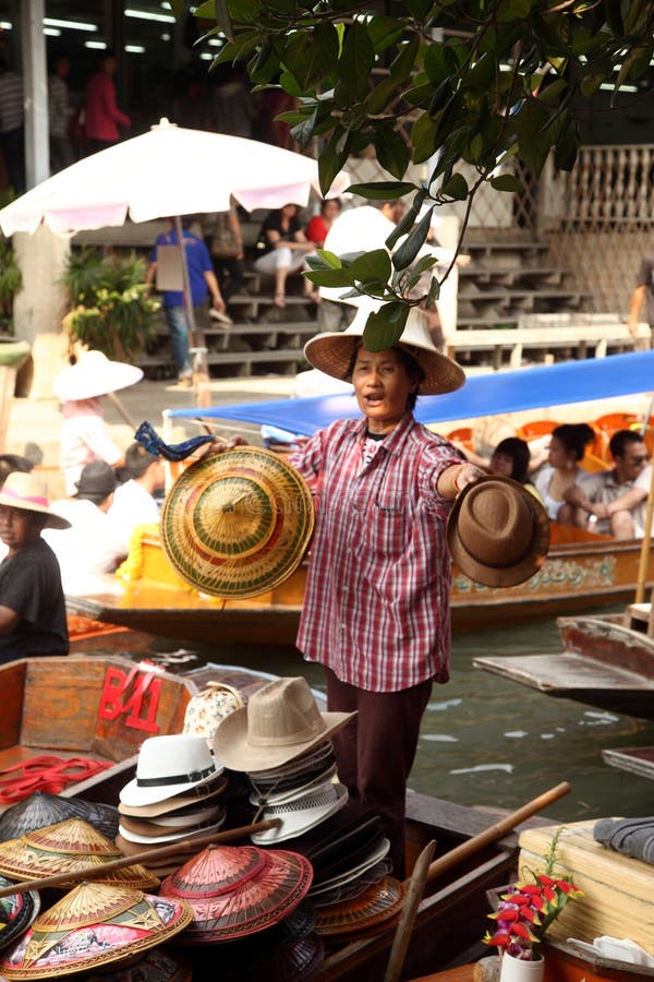 Damnoen Saduak floating market, A woman sell hats made of bamboo leaves at Damnoen Saduak floating market on February 13, 2011 in Ratchaburi, Thailand. Its popular for old and traditional way to sell and buy food.
