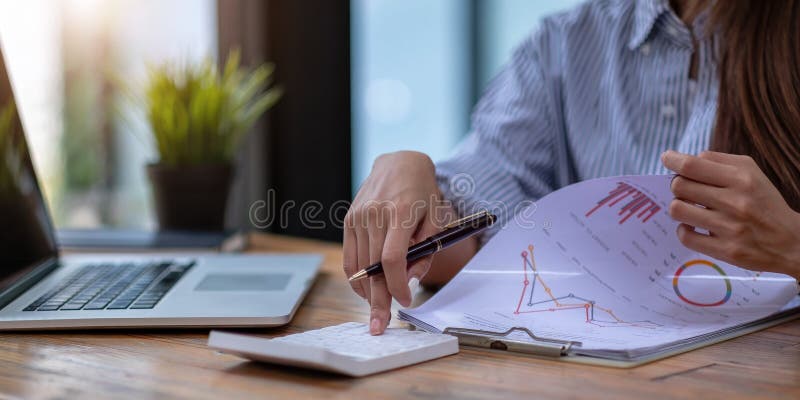 Close up Business woman using calculator and laptop for do math finance on wooden desk in office and business working background,, Close up Business woman using calculator and laptop for do math finance on wooden desk in office and business working background, tax, accounting, statistics and analytic research concept