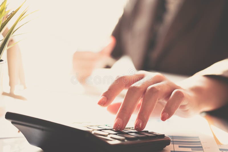 Close up Business woman using calculator and laptop for do math finance on wooden desk in office and business working background,, Close up Business woman using calculator and laptop for do math finance on wooden desk in office and business working background, tax, accounting, statistics and analytic research concept