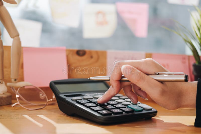 Close up Business woman using calculator and laptop for do math finance on wooden desk in office and business working background,, Close up Business woman using calculator and laptop for do math finance on wooden desk in office and business working background, tax, accounting, statistics and analytic research concept