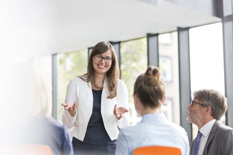 Smiling businesswoman planning strategy with colleagues during meeting at office, Smiling businesswoman planning strategy with colleagues during meeting at office