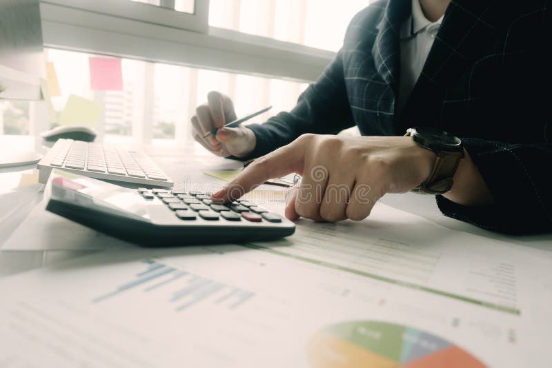 Close up Business woman using calculator and laptop for do math finance on wooden desk in office and business working background,, Close up Business woman using calculator and laptop for do math finance on wooden desk in office and business working background, tax, accounting, statistics and analytic research concept.