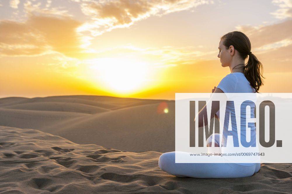 Woman practising yoga on sand dunes model released Symbolfoto DIGF000028