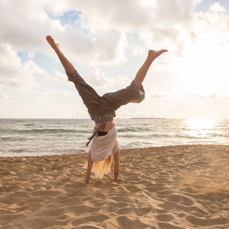 Free Happy Woman Turning Cartwheel Enjoying Sunset on Sandy Beach., Relaxed woman enjoying sun, freedom and life turning cartwheel on beautiful beach in sunset. Young lady feeling free, relaxed and happy. Vacations, freedom, happiness, enjoyment and well being. model released