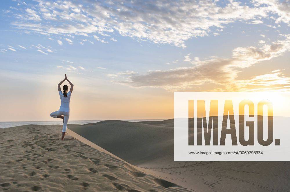 Woman practising yoga on sand dunes model released Symbolfoto DIGF000024