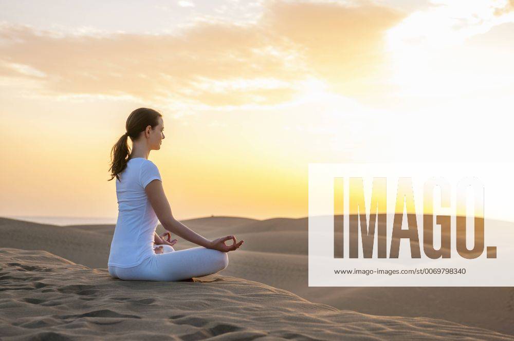 Woman practising yoga on sand dunes model released Symbolfoto DIGF000027