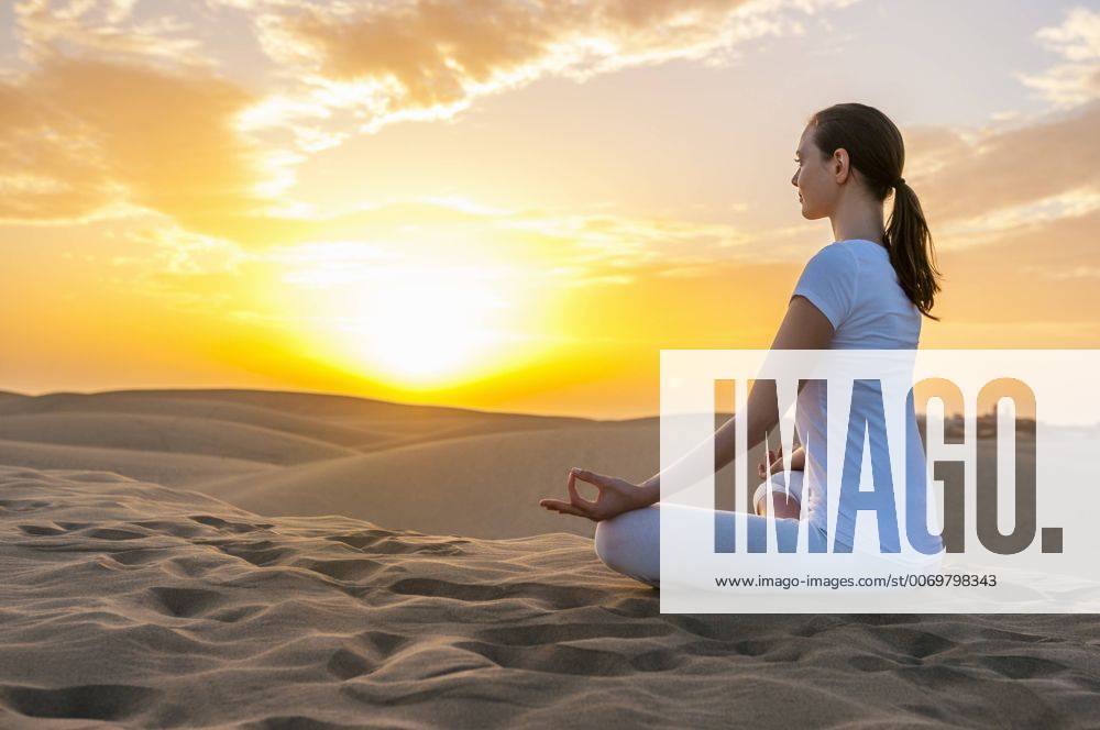 Woman practising yoga on sand dunes model released Symbolfoto DIGF000029