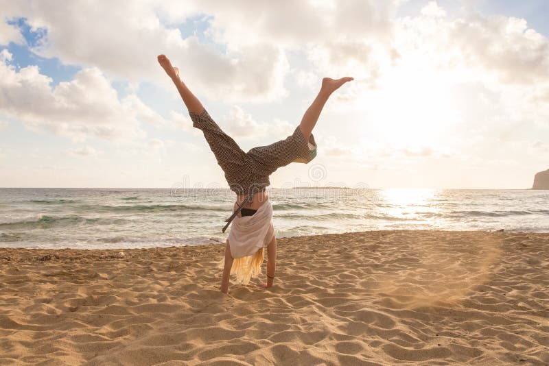 Free Happy Woman Turning Cartwheel Enjoying Sunset on Sandy Beach., Relaxed woman enjoying sun, freedom and life turning cartwheel on beautiful beach in sunset. Young lady feeling free, relaxed and happy. Vacations, freedom, happiness, enjoyment and well being. model released