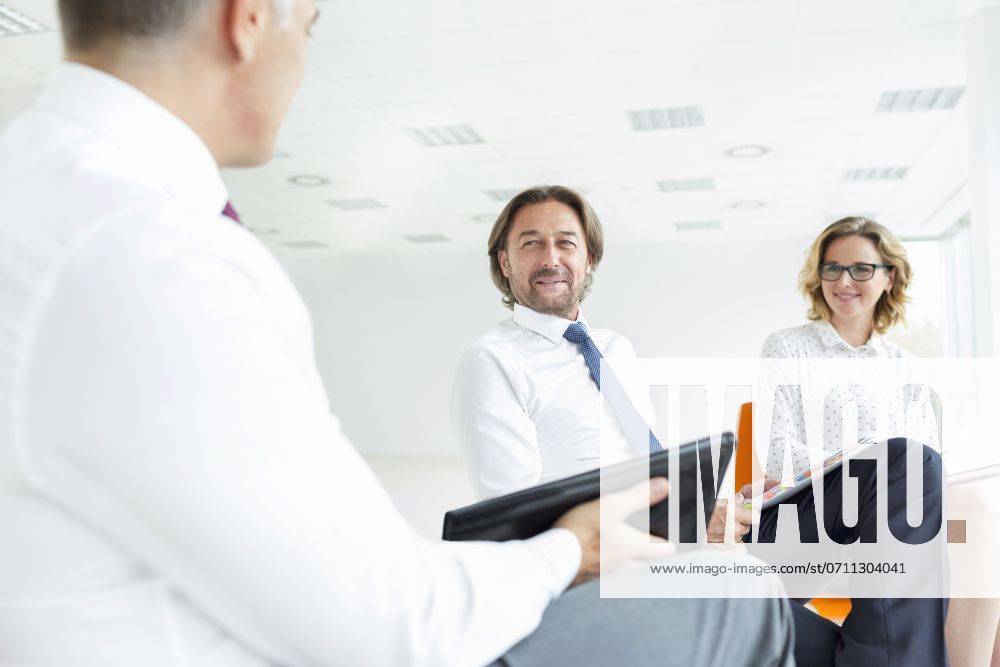 Smiling colleagues looking at businessman while sitting in new office during meeting ,model released, Symbolfoto
