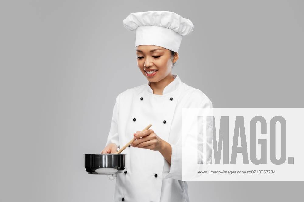 Culinary and people concept - happy smiling female chef in toque and jacket with saucepan cooking food over grey background. happy smiling female chef with saucepan ,model released, Symbolfoto