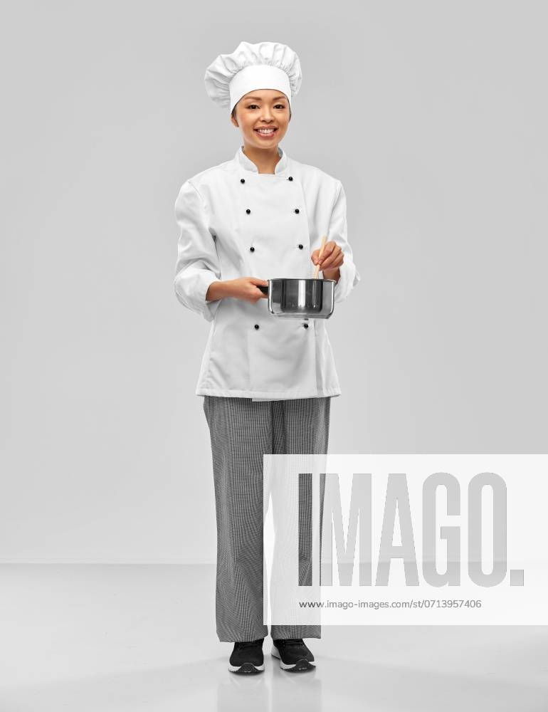 Culinary and people concept - happy smiling female chef in toque and jacket with saucepan cooking food over grey background. happy smiling female chef with saucepan ,model released, Symbolfoto