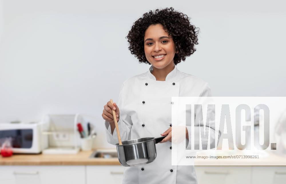 Culinary and people concept - happy smiling female chef in jacket with saucepan cooking food over restaurant kitchen background. happy smiling female chef with saucepan on kitchen ,model released, Symbolfoto