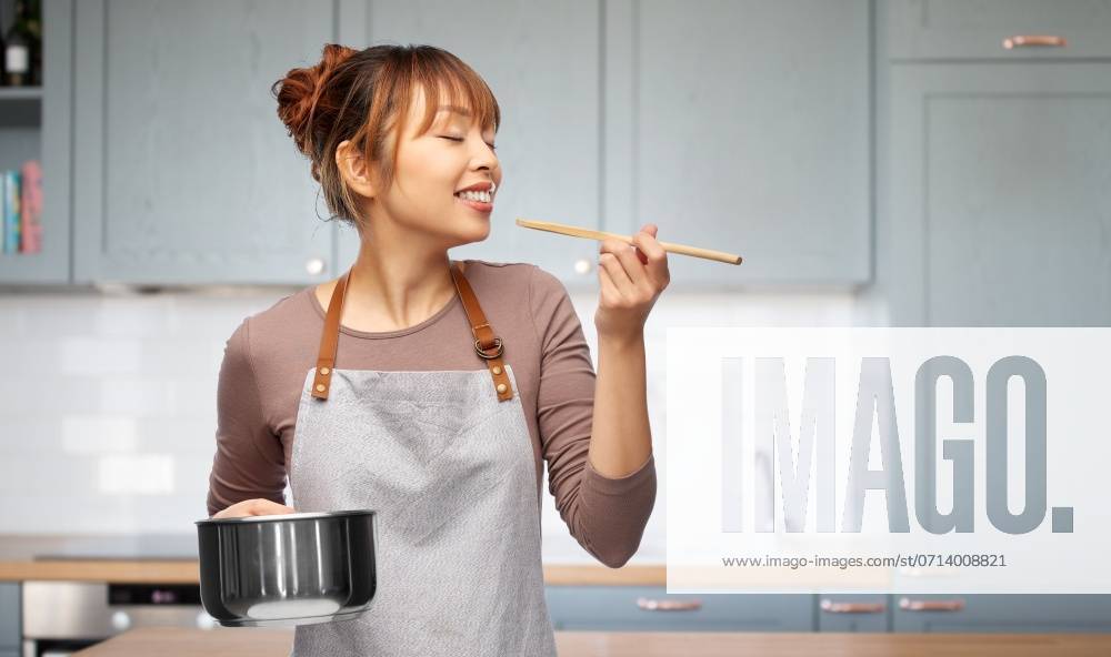 Culinary and people concept - happy smiling woman in apron with saucepan cooking food over kitchen background. happy woman in apron with saucepan in kitchen ,model released, Symbolfoto