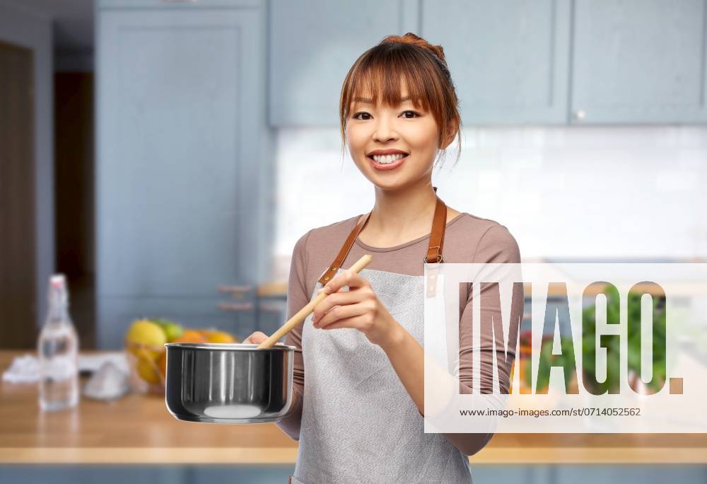 Culinary and people concept - happy smiling female chef in jacket with saucepan cooking food over home kitchen background. happy smiling female chef with saucepan in kitchen ,model released, Symbolfoto