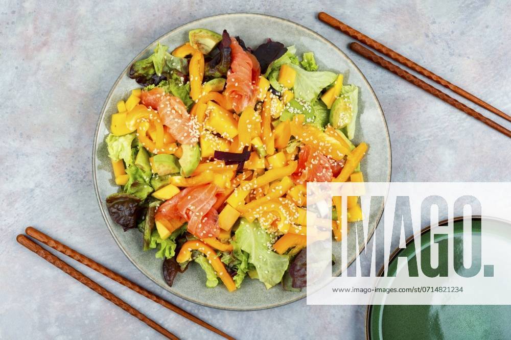 Tasty salad with salmon, mango, sesame avocado and pepper. Top view, food and chopsticks. Diet salad with salted salmon ,model released, Symbolfoto