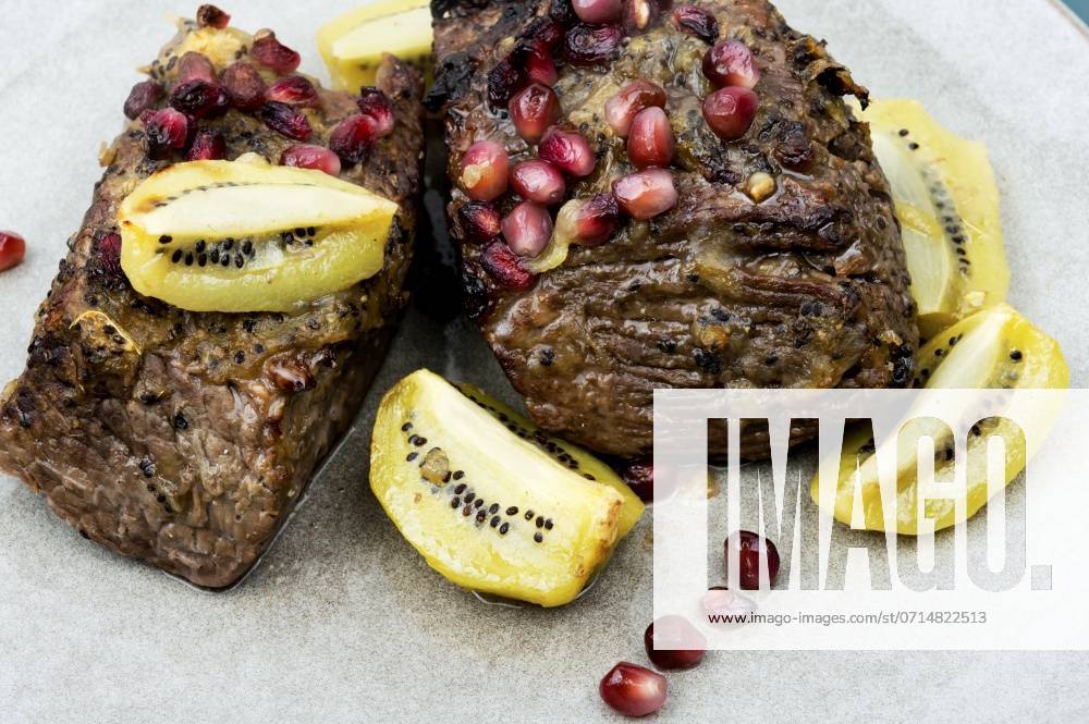 Cooked veal meat in kiwi and pomegranate sauce. Healthy food. Beef meat baked with kiwi and pomegranate. ,model released, Symbolfoto