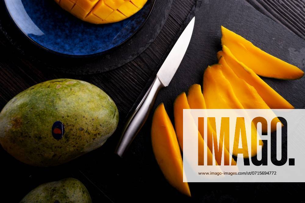 Ripe and tasty egyption Mango sleces and whole mango served at black dish. flat lay ,model released, Symbolfoto