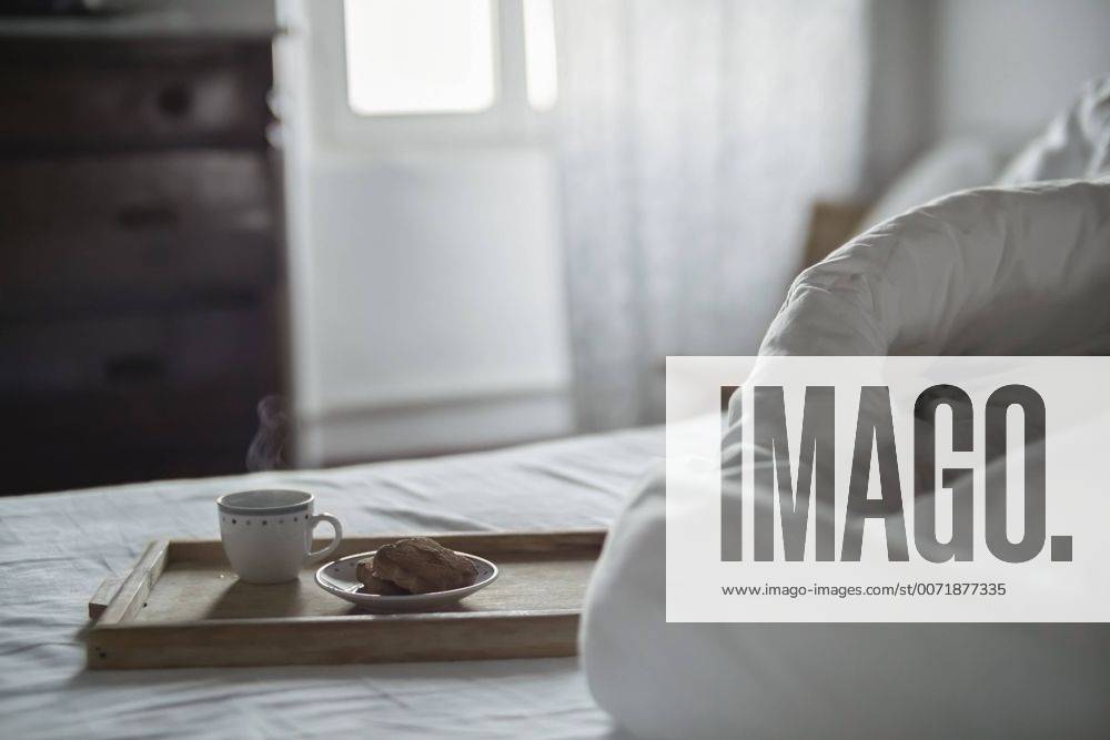 Wooden tray with cup of steaming coffee and biscuits on bed property released RIBF000401