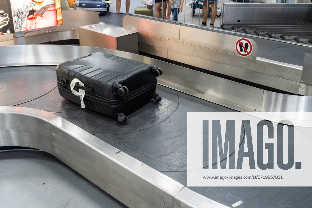 Ein schwarzer Koffer bewegt sich auf einem Gepäckband im Flughafen. Symbolbild Ankunft nach einer Flugreise und die Wartezeit auf das Reisegepäck