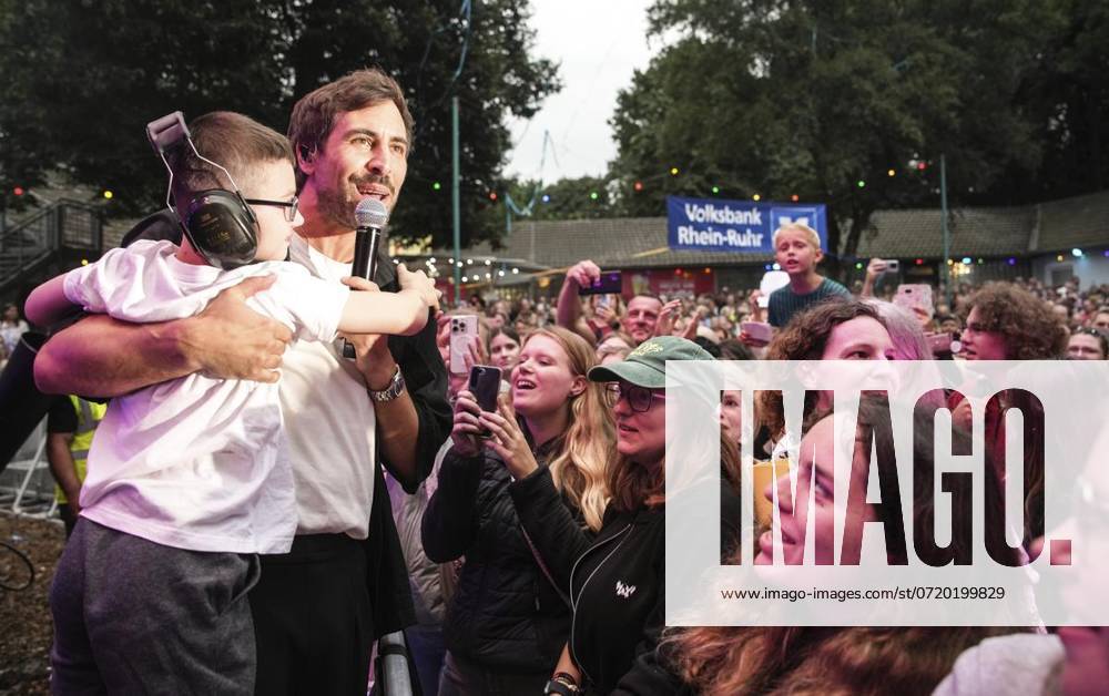 Schlagersänger Max Giesinger bei einem Auftritt im Stadtpark Meiderich in Duisburg am Samstag, 3. August 2024. Der Künstler ist ein Vertreter des deutschen Betroffenheitspop und findet damit sehr viel Anklang in Duisburg. Veranstalter Guido Jansen hat für ihn eine Gesangsanlage für 1,4 Millionen Euro aufgefahren. Er sieht einen kleinen Jungen und singt mit ihm zusammen. Duisburg NRW Duisburg