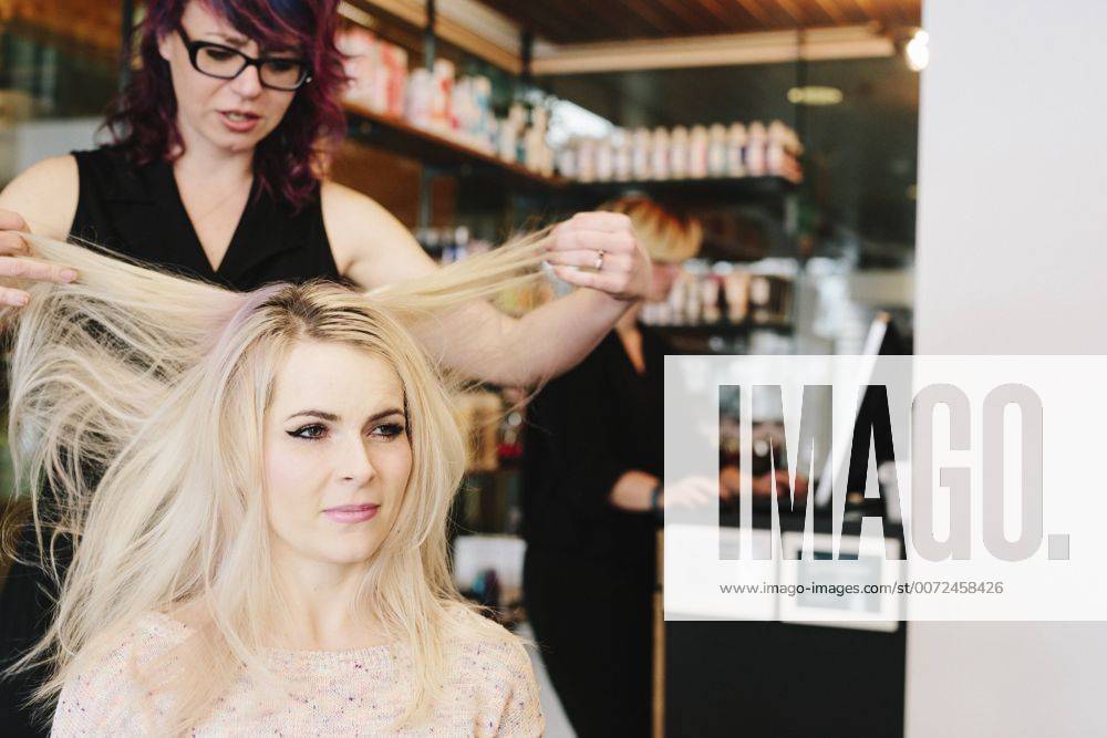 A hair stylist and a client, a young woman with long blonde hair, at a hair salon. A hair stylist and a client, a young woman with long blonde hair, at a hair salon. 21690