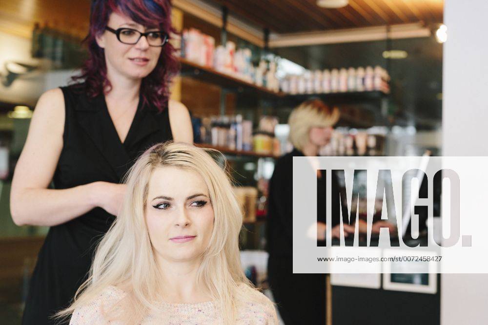 A hair stylist and a client, a young woman with long blonde hair, at a hair salon. A hair stylist and a client, a young woman with long blonde hair, at a hair salon. 21691