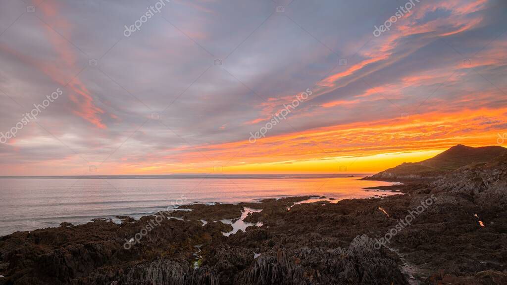 A horizontal view of the Woolacombe beach and surrounding nature under the beautiful sunset in July 2022