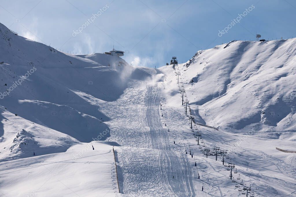 Ski lifts heading toward the top of the snow-capped mountains of Grandvalira from Pas de la Casa.