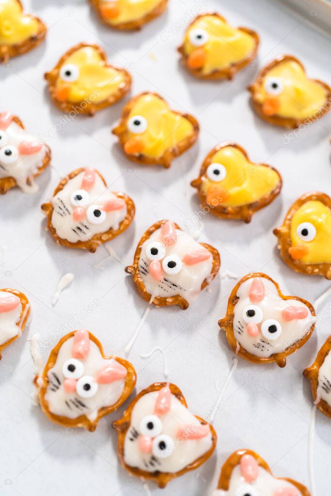 Preparing Easter chocolate-covered pretzel bunnies and ducklings with white and yellow chocolate.