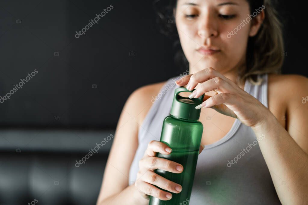 Detailed view of a girl uncorking her water bottle, after exercising at home