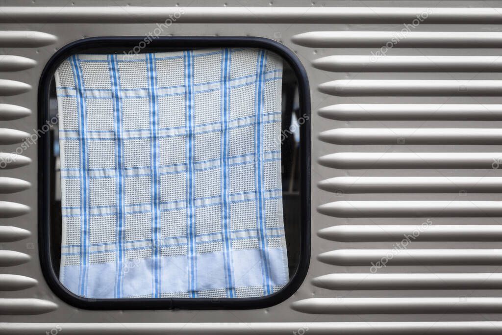 Silver streamlined travel trailer window covered by dish towel (copy space)