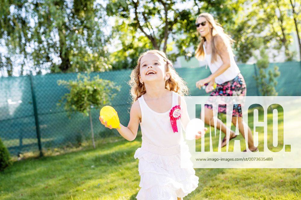 Little girl having fun with water bombs in the garden model released Symbolfoto property released HAPF000764
