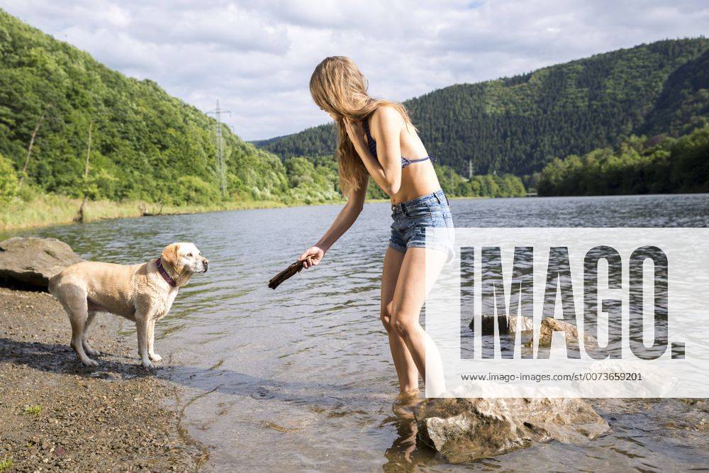 Young woman playing with her dog in a lake model released Symbolfoto property released FMKF002796