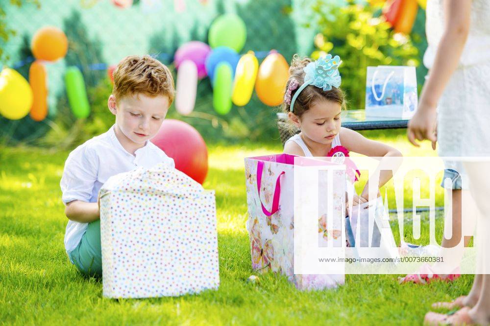 Little boy and girl unpacking birthday presents in the garden model released Symbolfoto HAPF000740