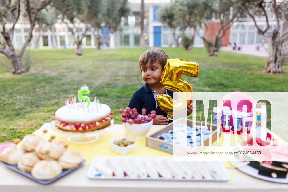 Little boy with golden balloon behind laid birthday table model released Symbolfoto VABF00770